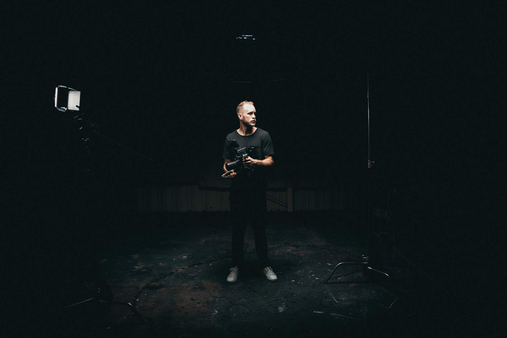 man-holding-videocamera-standing-in-studio-3379943